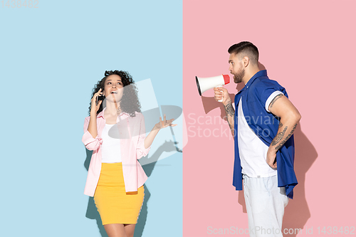 Image of Young emotional man and woman on pink and blue background