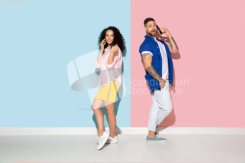 Image of Young emotional man and woman on pink and blue background