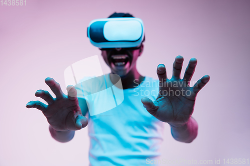 Image of Young african-american man\'s using VR-glasses in neon light