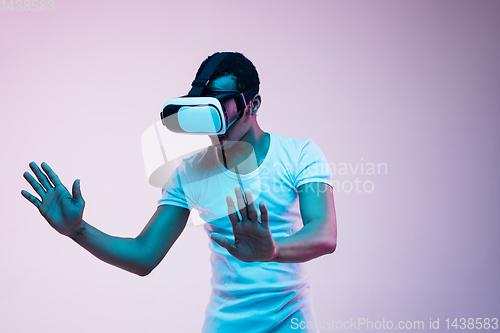 Image of Young african-american man\'s using VR-glasses in neon light