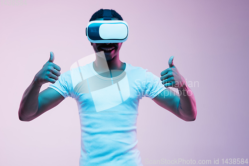 Image of Young african-american man\'s using VR-glasses in neon light