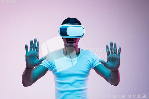 Image of Young african-american man\'s using VR-glasses in neon light