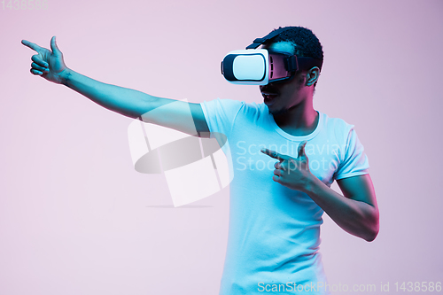 Image of Young african-american man\'s using VR-glasses in neon light