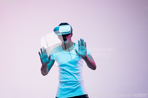 Image of Young african-american man\'s using VR-glasses in neon light