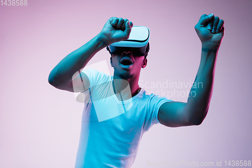 Image of Young african-american man\'s using VR-glasses in neon light