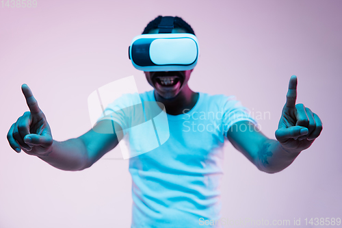Image of Young african-american man\'s using VR-glasses in neon light