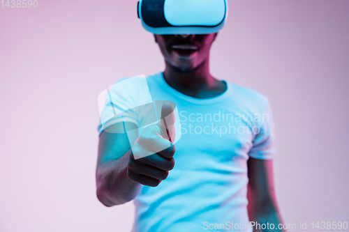 Image of Young african-american man\'s using VR-glasses in neon light