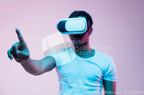 Image of Young african-american man\'s using VR-glasses in neon light