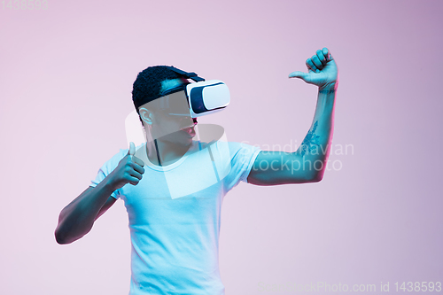 Image of Young african-american man\'s using VR-glasses in neon light