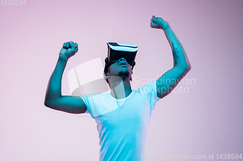 Image of Young african-american man\'s using VR-glasses in neon light