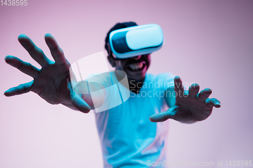 Image of Young african-american man\'s using VR-glasses in neon light