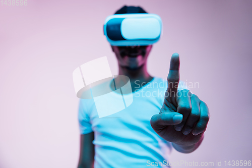 Image of Young african-american man\'s using VR-glasses in neon light