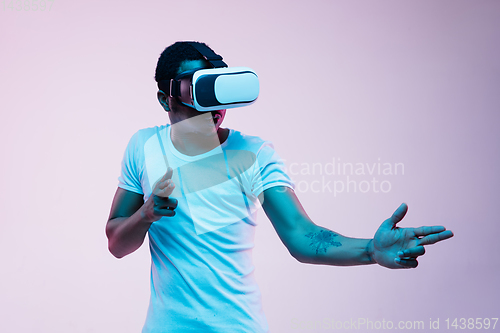 Image of Young african-american man\'s using VR-glasses in neon light