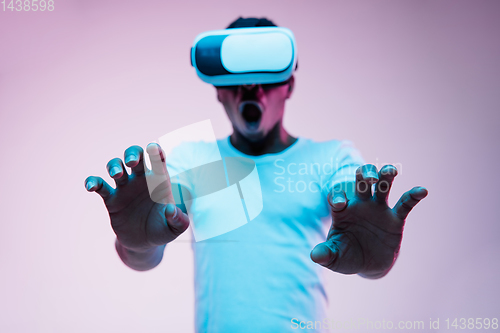 Image of Young african-american man\'s using VR-glasses in neon light