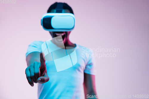 Image of Young african-american man\'s using VR-glasses in neon light