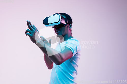Image of Young african-american man\'s using VR-glasses in neon light