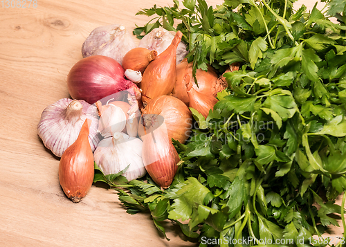 Image of garlic onion shallot parsley on a wooden board