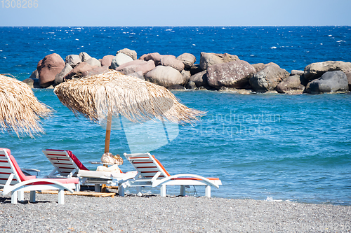 Image of beach with umbrellas and deck chairs by the sea in Santorini