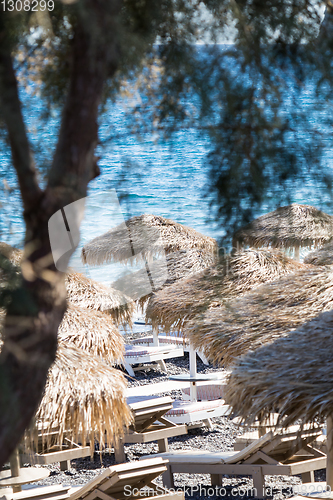 Image of beach with umbrellas and deck chairs by the sea in Santorini