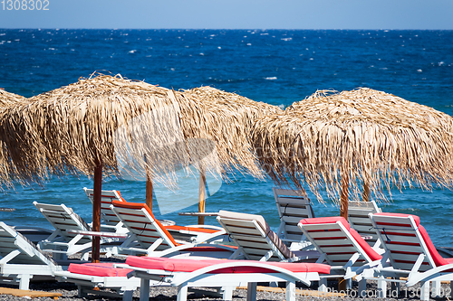 Image of beach with umbrellas and deck chairs by the sea in Santorini