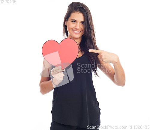 Image of beautiful happy brunette woman holding and showing a big red hea