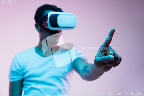 Image of Young african-american man\'s using VR-glasses in neon light