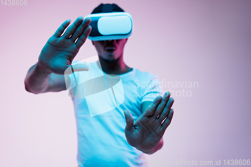 Image of Young african-american man\'s using VR-glasses in neon light