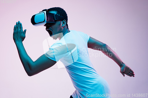 Image of Young african-american man\'s using VR-glasses in neon light