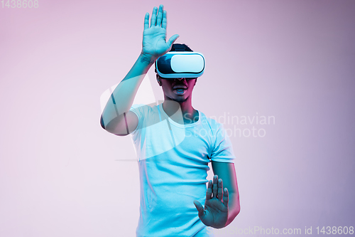 Image of Young african-american man\'s using VR-glasses in neon light