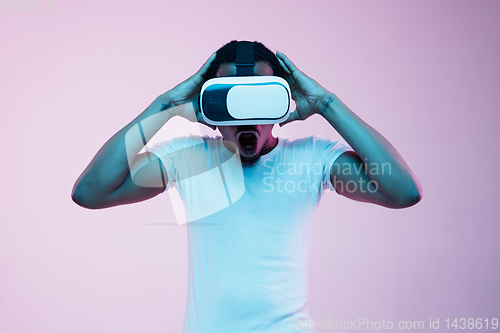 Image of Young african-american man\'s using VR-glasses in neon light