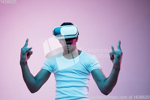 Image of Young african-american man\'s using VR-glasses in neon light