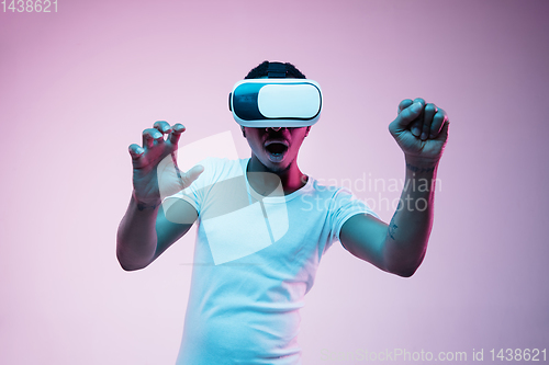 Image of Young african-american man\'s using VR-glasses in neon light