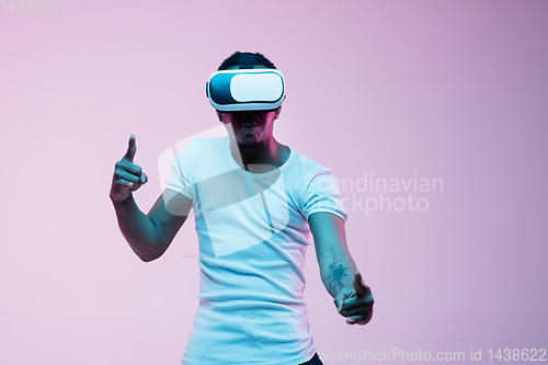 Image of Young african-american man\'s using VR-glasses in neon light