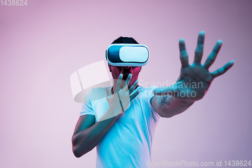 Image of Young african-american man\'s using VR-glasses in neon light