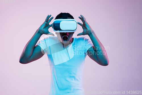 Image of Young african-american man\'s using VR-glasses in neon light