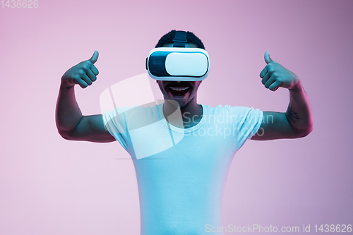 Image of Young african-american man\'s using VR-glasses in neon light