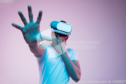 Image of Young african-american man\'s using VR-glasses in neon light