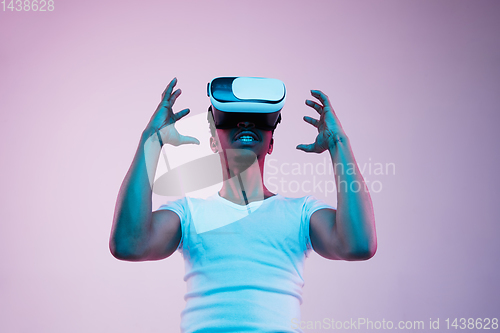 Image of Young african-american man\'s using VR-glasses in neon light