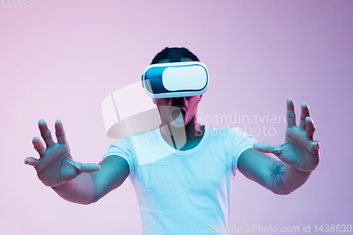 Image of Young african-american man\'s using VR-glasses in neon light