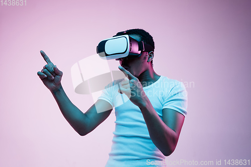 Image of Young african-american man\'s using VR-glasses in neon light