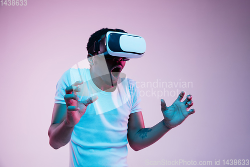 Image of Young african-american man\'s using VR-glasses in neon light