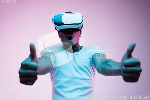 Image of Young african-american man\'s using VR-glasses in neon light