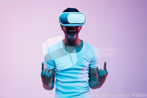 Image of Young african-american man\'s using VR-glasses in neon light