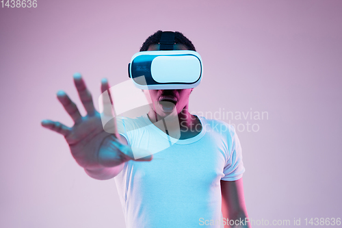 Image of Young african-american man\'s using VR-glasses in neon light