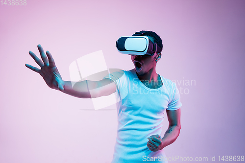 Image of Young african-american man\'s using VR-glasses in neon light