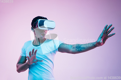 Image of Young african-american man\'s using VR-glasses in neon light