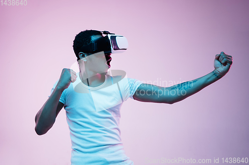 Image of Young african-american man\'s using VR-glasses in neon light