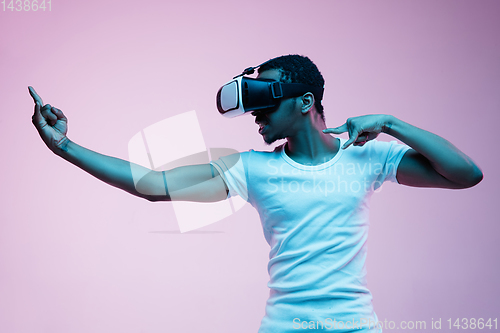 Image of Young african-american man\'s using VR-glasses in neon light