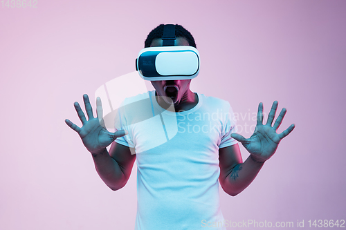 Image of Young african-american man\'s using VR-glasses in neon light