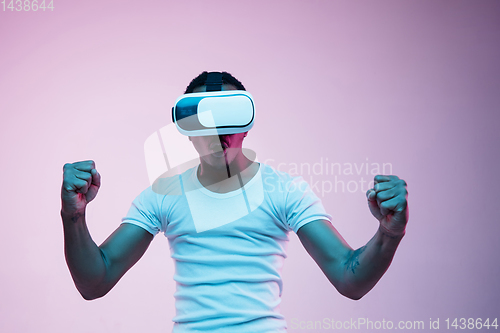 Image of Young african-american man\'s using VR-glasses in neon light